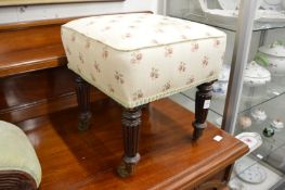 A 19th century upholstered stool on turned and reeded legs with brass castors.