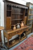 An 18th century design oak dresser with delft rack, having two small cupboards above a pot board