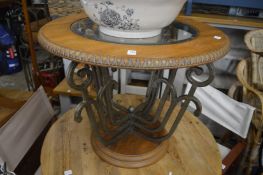 An oak glass and wrought iron circular occasional table.