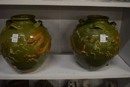 A pair of Chinese or Korean green glazed pots with moulded dragon decoration.