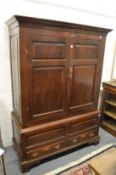 An 18th century oak linen press cupboard with a pair of doors enclosing hanging rails above a base