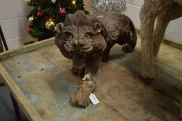 A pair of weathered carved wood models of prowling lions.
