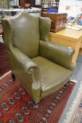 A George III design green leather upholstered wing armchair.