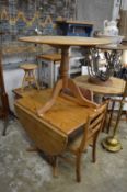 A pine circular tripod table together with a modern pine drop-leaf table and a chair.