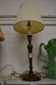A turned wood candlestick style table lamp.