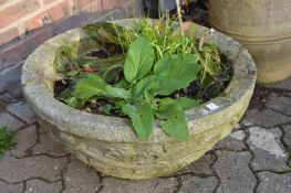 A large reconstituted stone circular planter.