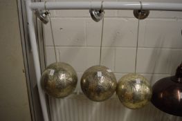 A set of three pierced metal globe shaped ceiling lights.