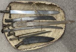 Bundle of swords etc including a tulwar, kukri, bayonet, Brown Bess bayonet, decorative broad