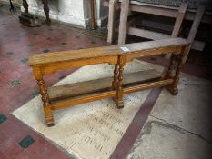 An early 20th century long oak prie-dieu or communion rail raised over baluster supports,