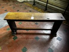 A stout 19th century oak straight-shaped organ bench raised over solid supports united by a plain