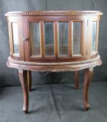 A curiosities or cocktail cabinet having bevelled edge glass panels throughout.