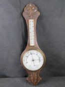 An Edwardian Aneroid barometer, carved oak case with thermometer over,