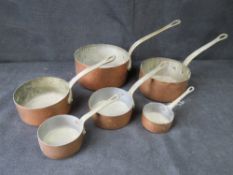 A set of six graduated copper saucepans.