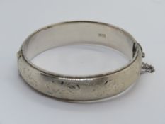 A hallmarked silver hinged bangle having floral engraving throughout.