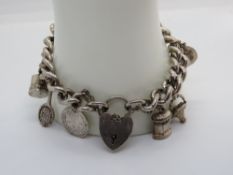 A heavy silver charm bracelet, chain with rampant lion mark throughout, various charms,