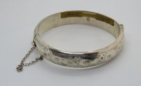 A hallmarked silver hinged bangle with floral engraving to front.