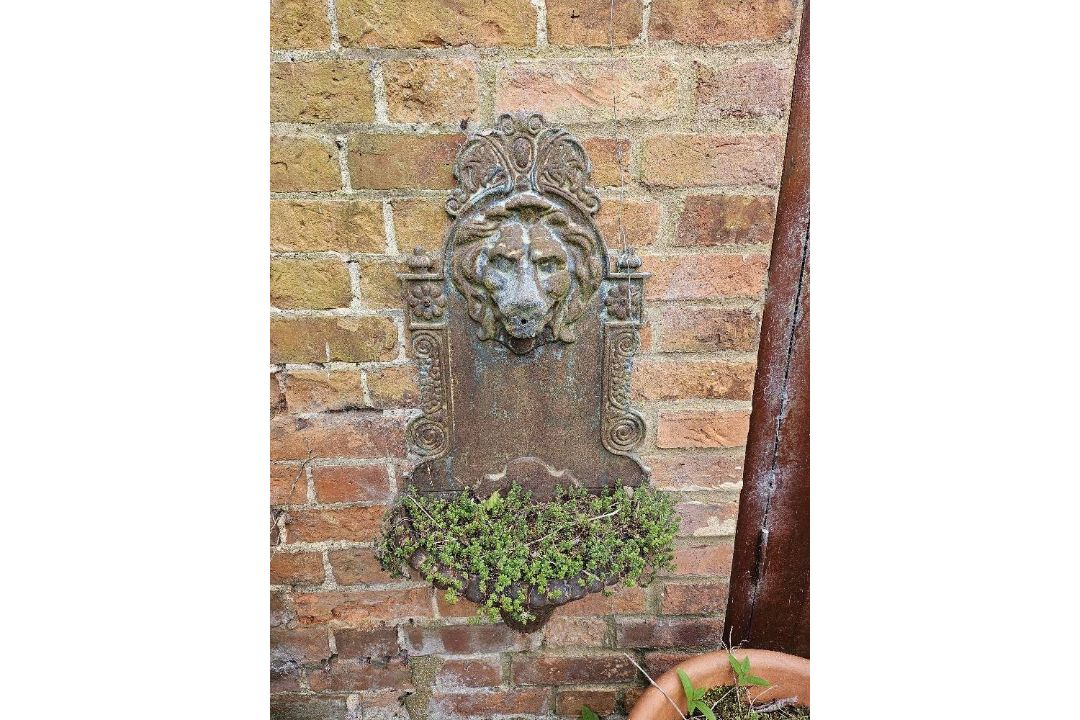 A cast iron lion heads wall fountain, 80 x 40cm.