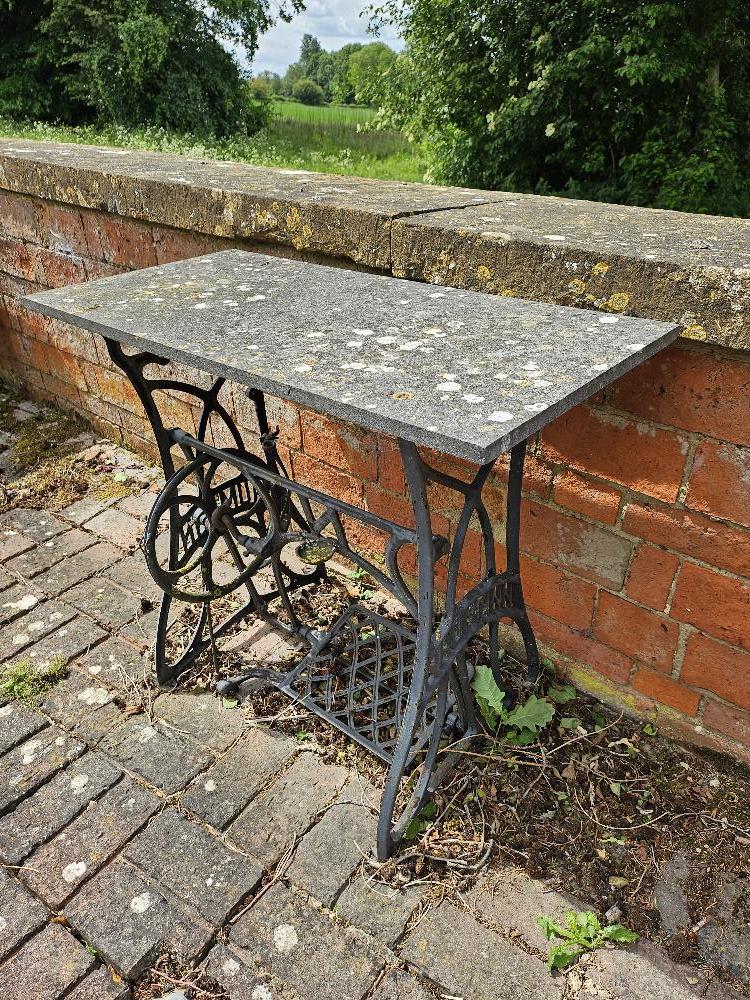 A Naumann sewing machine table base with stone top.