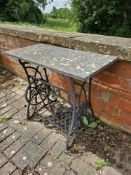 A Naumann sewing machine table base with stone top.