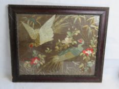 A silk needlework depicting two birds in foliage, framed and glazed.
