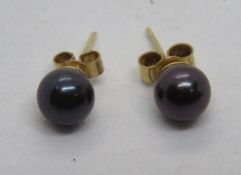 A pair of black pearl stud earrings, 9ct marks to butterfly backs.