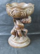 A carved wooded planter stand having cherub lifting a heavy bowl, standing 51cm high.