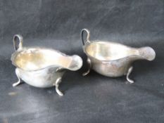 A pair of hallmarked silver sauce boats having pie crust edge and raised over three outswept feet,