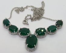 A silver necklace having central articulated panel of six graduated oval cut green stones with
