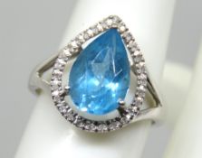 A modern design 9ct white gold cocktail ring set with blue teardrop topaz with white stone 'halo'