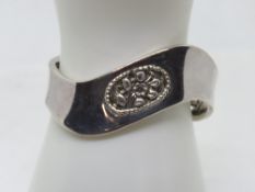 A silver bangle having carved floral decorative panels, stamped 925, 28.6g.