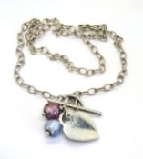A hallmarked silver necklace with glass bead and heart tag pendant.