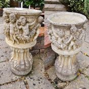 A pair of small decorative cast concrete planters, each 60cm high.