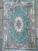 A Chinese woollen and silk green ground rug with floral panels, 200 x 120cm.