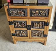 An oriental two door cabinet with six panels in relief to the front and gilded decoration to each