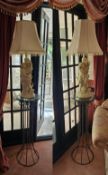 A pair of contemporary blacksmith type glass top torchere stands, each bearing a neoclassical style