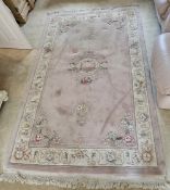 A 20th century woollen oriental rug, pink ground with floral panels, 270 x 156cm.