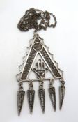 A large filigree pendant having hand design within triangle and having fringe below,