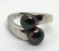 A silver ring set with two coloured pearls, size K.
