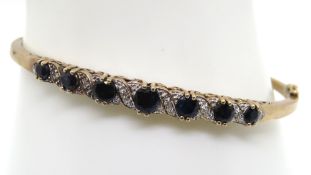 A classic sapphire and diamond 9ct gold bangle, hinged, hallmarked 375, 10.8g.