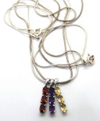 Three silver birthstone pendants on twin silver chains.