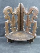 A black forest type carved wooden corner shelf having hinged shelf.