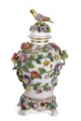 A Dresden porcelain vase of baluster form decorated in relief with flowers and birds, the cover with