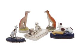 A collection of 19th Century Staffordshire greyhounds including one seated on a cushion with a
