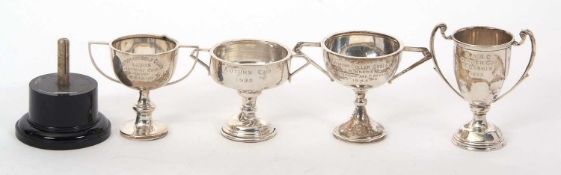 A group of four hallmarked silver small twin handled trophies, three with presentation engraving and