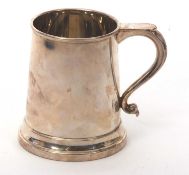 An Elizabeth II silver mug of plain cylindrical tapering form with a scroll handle, hallmarked for