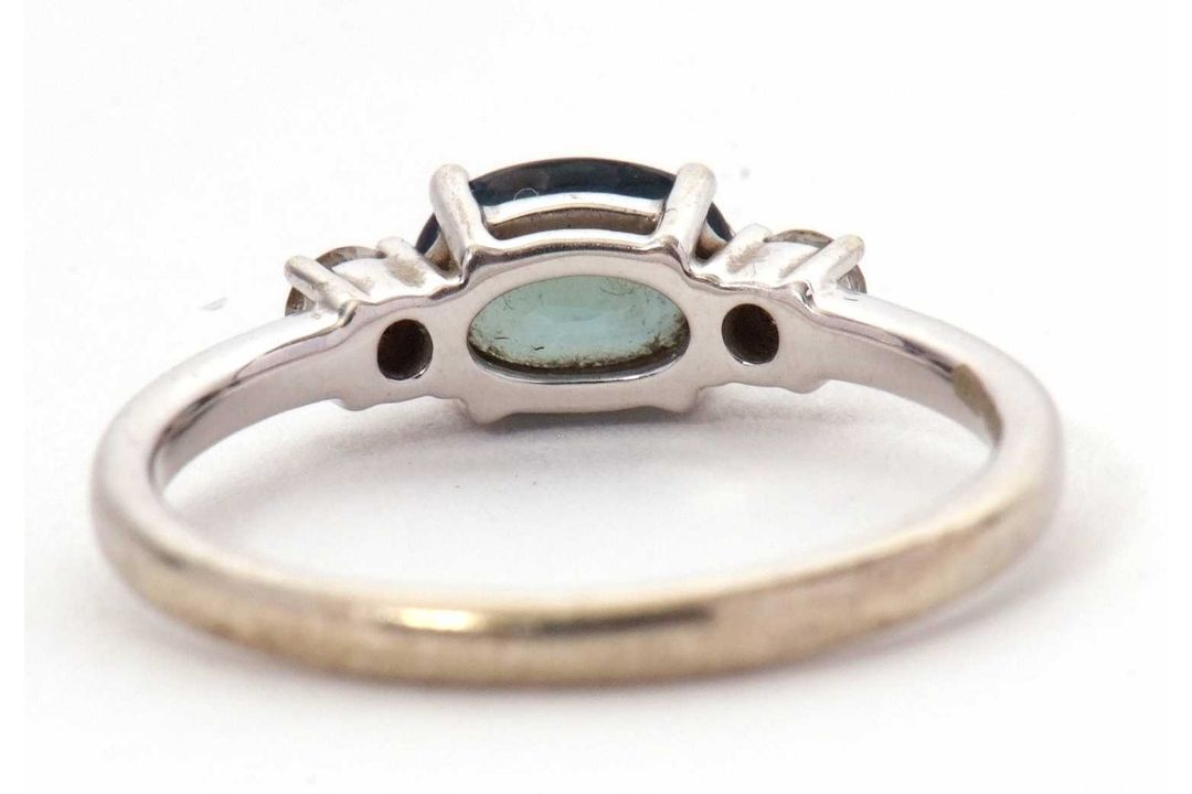 A 9ct sapphire and diamond ring, the oval blue-green sapphire set to either side with a round - Image 5 of 8