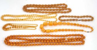 A quantity of faux amber: to include a graduated oval barrel shape bead necklace, a long oval bead