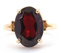 A 14ct garnet ring, the oval mixed cut garnet, approx. 13mm long, in a four claw mount with plain
