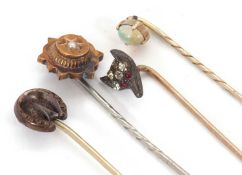 Four stick pins: to include a fox head pin set with white and red paste; an oval opal cabochon