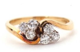 A diamond ring, the crossover style ring set with two trefoils of small round mixed cut diamonds,